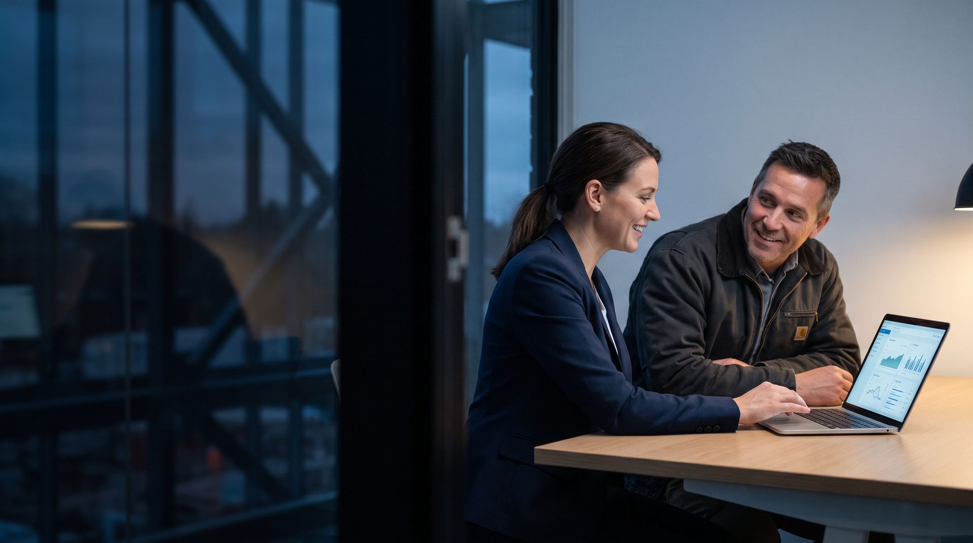 A financial advisor and a construction business owner reviewing figures together on a laptop